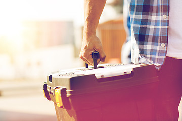 Image showing close up of builder carrying toolbox outdoors