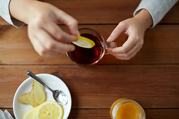 Image showing close up of woman adding lemon to tea cup