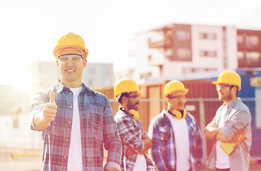 Image showing group of smiling builders in hardhats outdoors