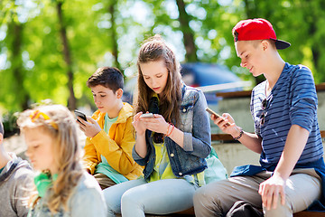 Image showing happy teenage friends with smartphones outdoors