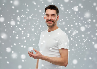 Image showing happy young man with cream jar over snow