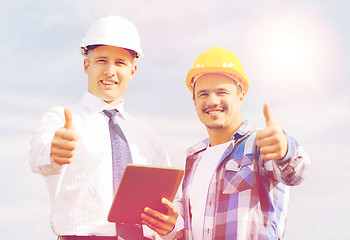 Image showing smiling builders in hardhats with tablet pc