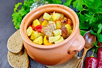 Image showing Roast meat and vegetables in clay pot on board