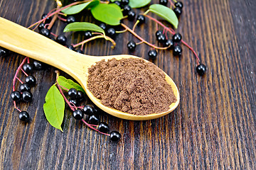 Image showing Flour bird cherry in spoon with berries on wooden board