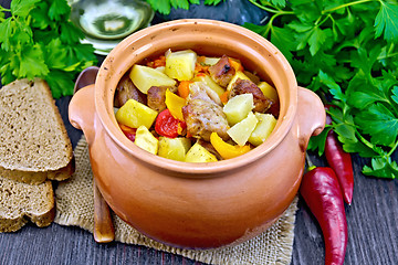 Image showing Roast meat and potatoes in clay pot on dark board