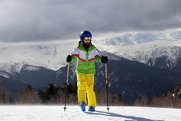 Image showing Young skier with ski poles in sun mountains and gray sky before 