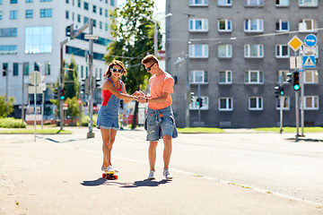 Image showing teenage couple riding skateboards on city street