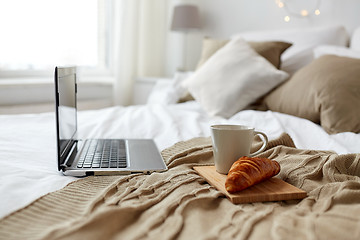 Image showing laptop, coffee and croissant on bed at cozy home