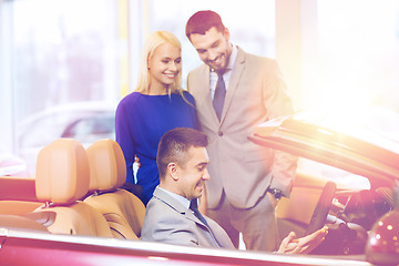 Image showing happy couple with car dealer in auto show or salon