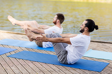 Image showing men making yoga in half-boat pose outdoors