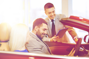 Image showing happy couple with car dealer in auto show or salon