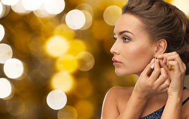 Image showing close up of woman fastening diamond earring