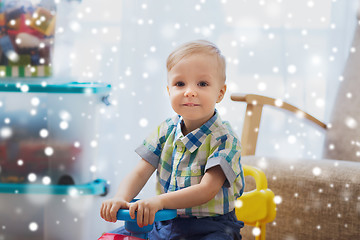 Image showing happy little baby boy driving ride-on car at home