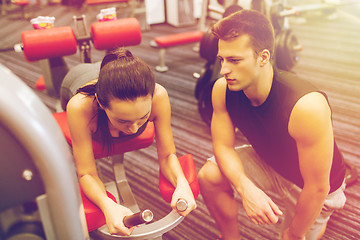 Image showing young woman with trainer exercising on gym machine