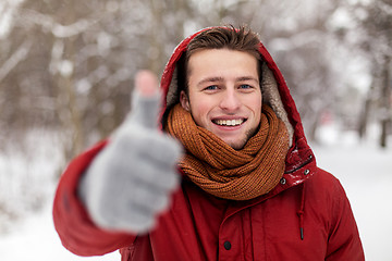 Image showing happy man in winter jacket showing thumbs up