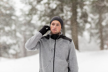 Image showing sports man with earphones in winter forest