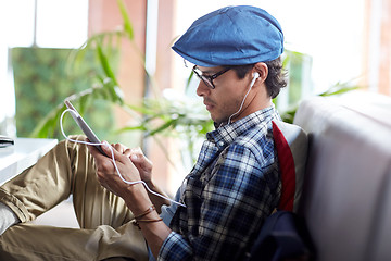 Image showing man with tablet pc and earphones sitting at cafe