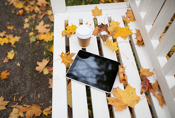 Image showing tablet pc and coffee cup on bench in autumn park