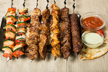 Image showing set shashlik. kebab skewer, black rectangular plate. sauce and onions