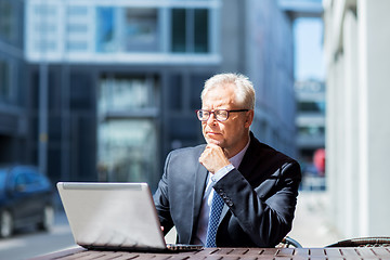 Image showing senior businessman with laptop at city street cafe