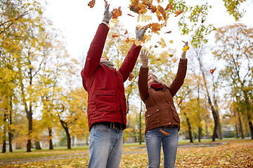 Image showing happy young couple throwing autumn leaves in park