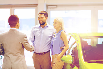 Image showing happy couple with car dealer in auto show or salon