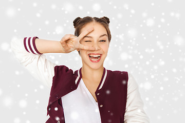 Image showing happy teenage girl showing peace sign over snow