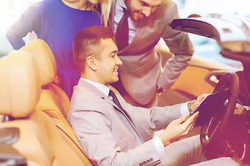 Image showing happy couple with car dealer in auto show or salon