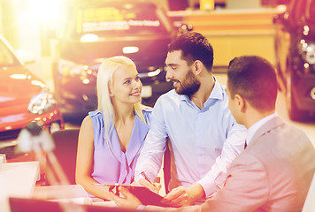 Image showing happy couple with car dealer in auto show or salon