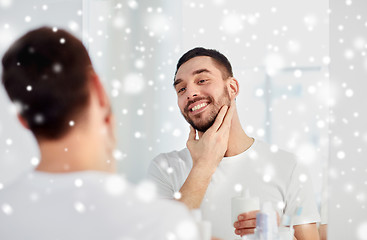 Image showing happy man applying aftershave at bathroom mirror