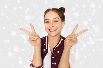 Image showing happy teenage girl showing peace sign over snow