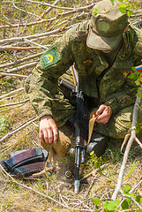 Image showing Soldier cools submachine gun barrel by water