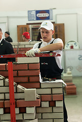 Image showing Young bricklayer performs a task of competition