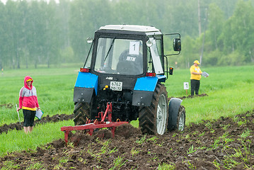 Image showing Tractor operator plows the site in rain. Tyumen