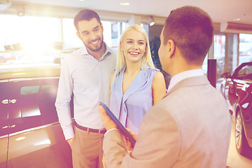 Image showing happy couple with car dealer in auto show or salon