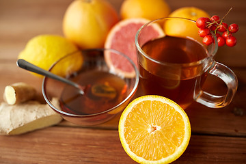 Image showing tea with honey, orange and rowanberry on wood