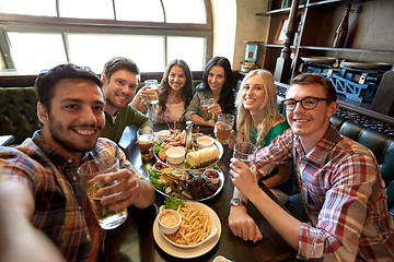 Image showing happy friends taking selfie at bar or pub