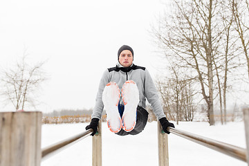 Image showing young man exercising on parallel bars in winter