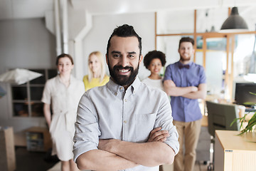 Image showing happy young man over creative team in office