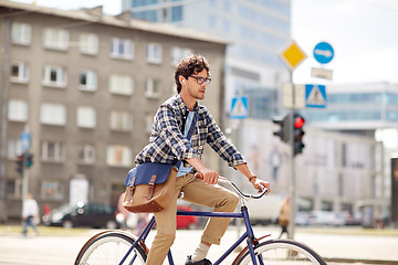 Image showing young hipster man with bag riding fixed gear bike