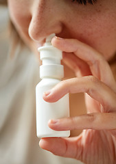 Image showing close up of sick woman using nasal spray