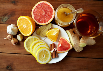 Image showing ginger tea with honey, citrus and garlic on wood