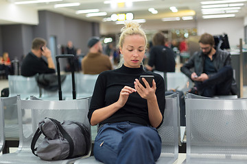 Image showing Lady using smart phone while waiting at airpot departure gates.
