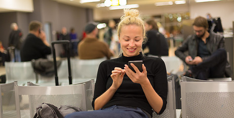 Image showing Lady using smart phone while waiting at airpot departure gates.