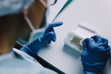 Image showing Crop hands putting microscope glasses in box