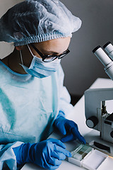 Image showing Female scientist arranging microscope glasses in box