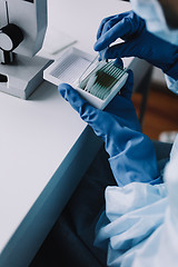 Image showing Crop hands putting microscope glasses in box