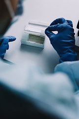 Image showing Crop hands putting microscope glasses in box