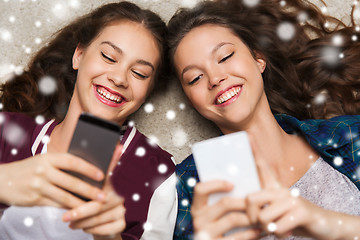 Image showing happy teenage girls lying on floor with smartphone