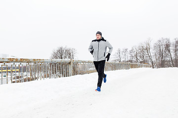 Image showing man running along snow covered winter bridge road